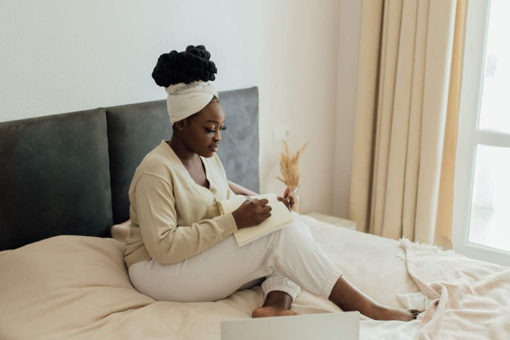 A young woman in cozy pajamas, sitting on a bed surrounded by soft pillows and fairy lights, holding a cup of herbal tea and reading a book, creating a peaceful and relaxing atmosphere for her nighttime routine.