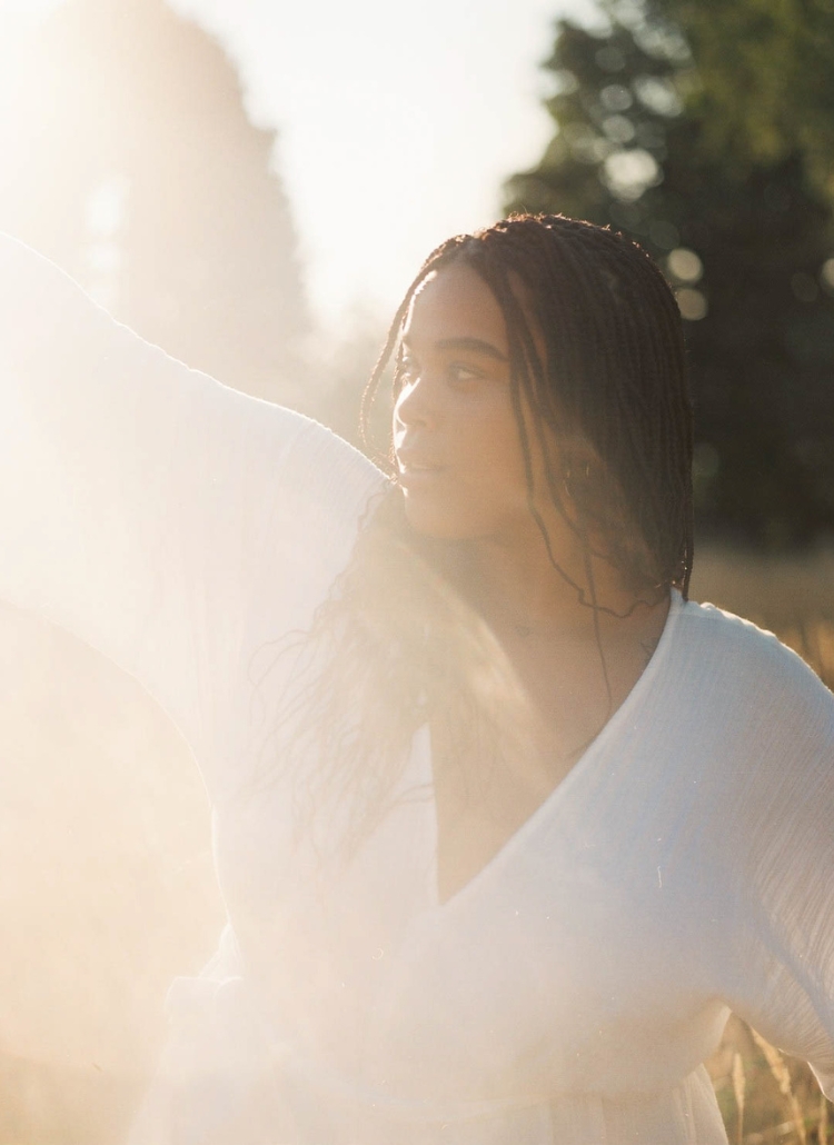 A wellness enthusiastic woman in a white dress standing in a field, perfect for a blog post on manifestation affirmations