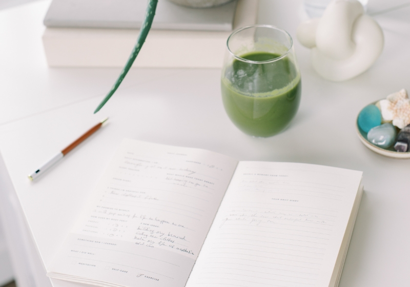  Image of a green smoothie and notebook on a desk, great for morning journal prompts.