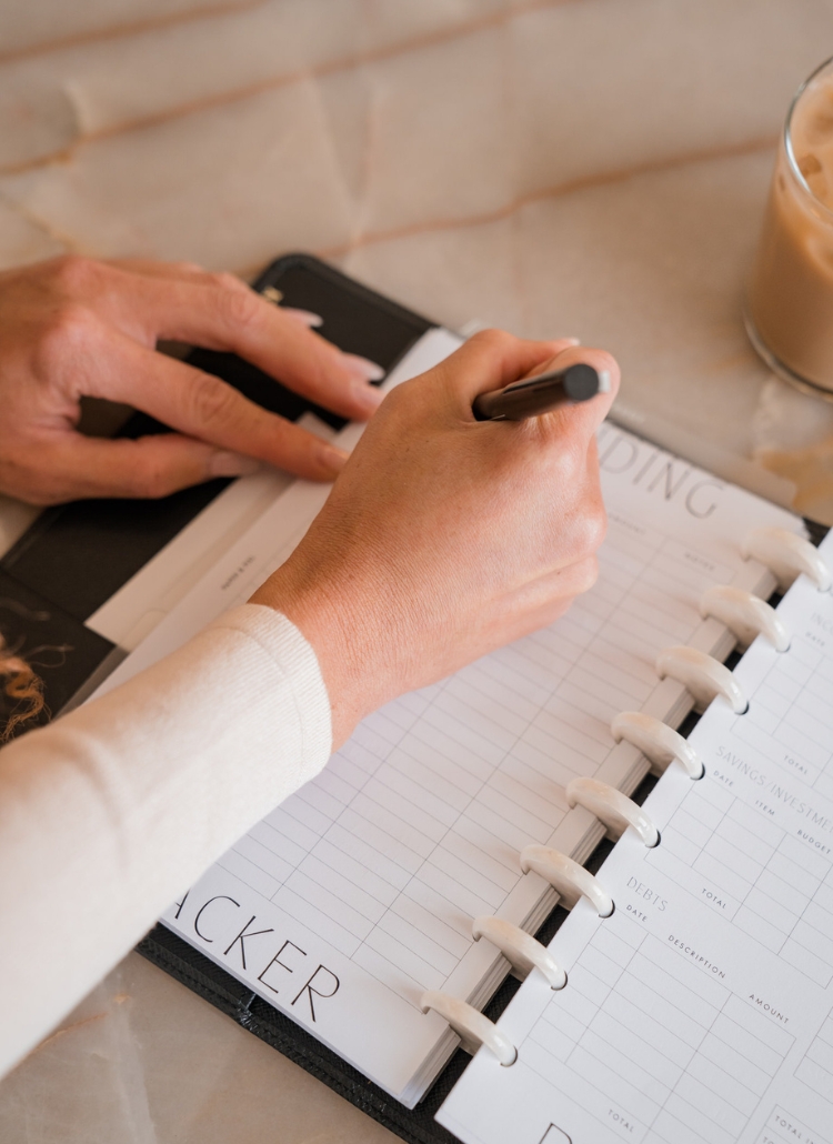 A woman's hand elegantly writes in a journal - a featured image in a or a blog post on manifestation journal prompts.