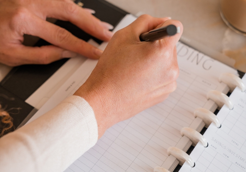 A woman's hand elegantly writes in a journal - a featured image in a or a blog post on journal prompt ideas for manifestation