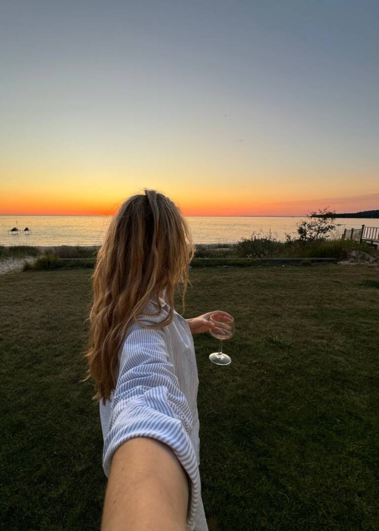 A woman with a glass of wine at sunset, capturing a serene moment ideal for aesthetic things to do when bored