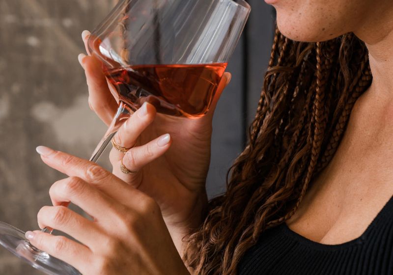 A woman in braids  enjoying a glass of  red wine - an image for a blog post about aesthetic things to do when bored